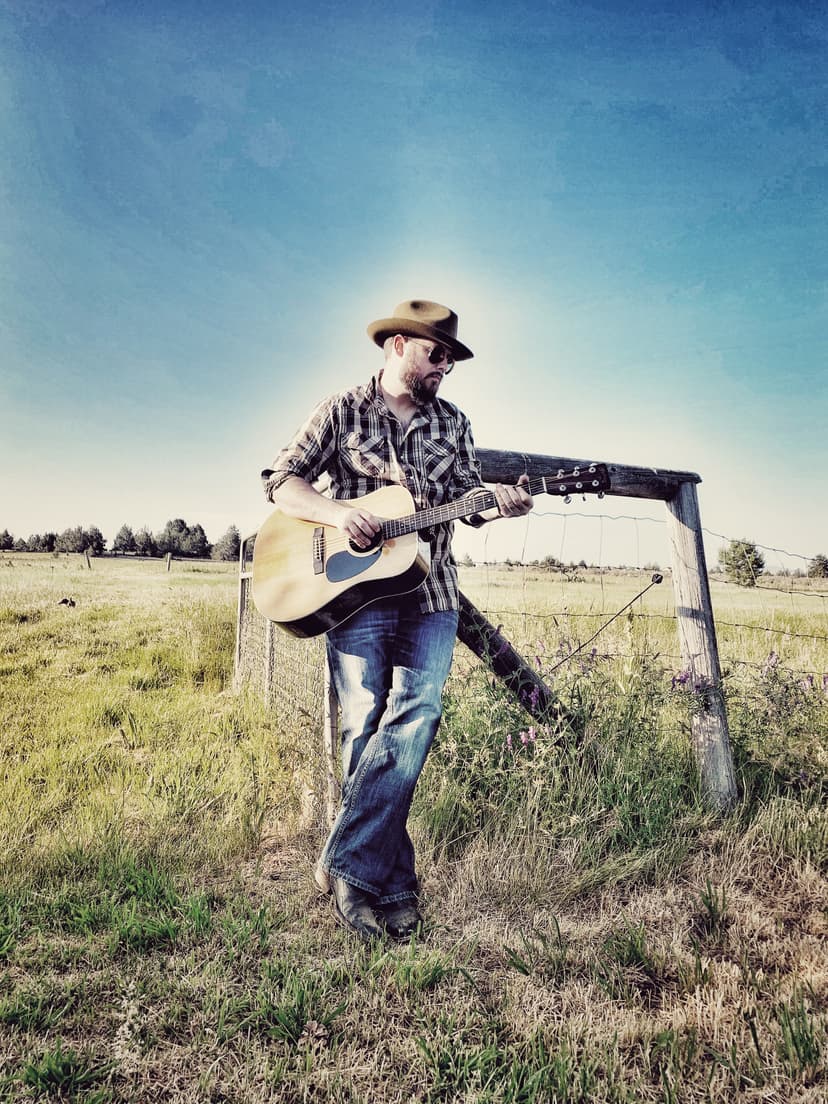 Sean Anthony Sullivan stands with Martin acoustic guitar in field.